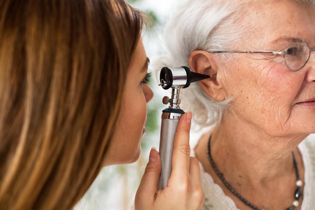 Elderly woman having ear inspected by doctor.