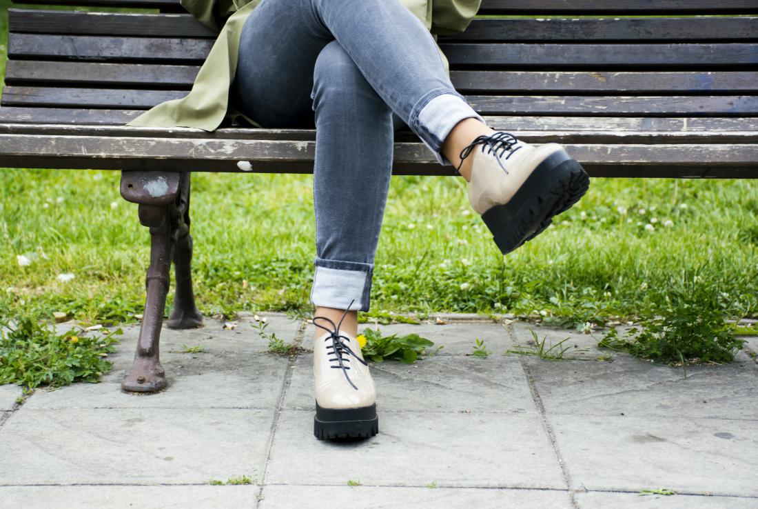Woman sat on a bench with her legs crossed which may cause numbness in legs and feet