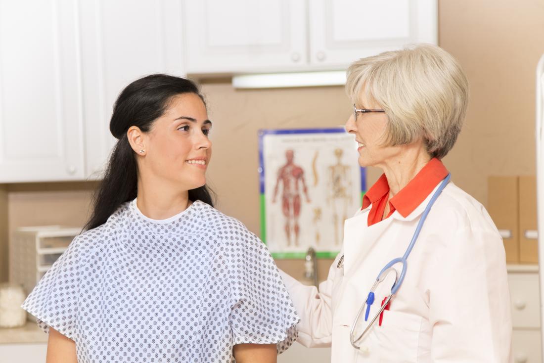 Woman in hospital gown listening to doctor.
