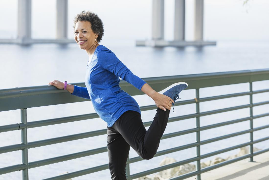 Older woman stretching her leg in running clothes.