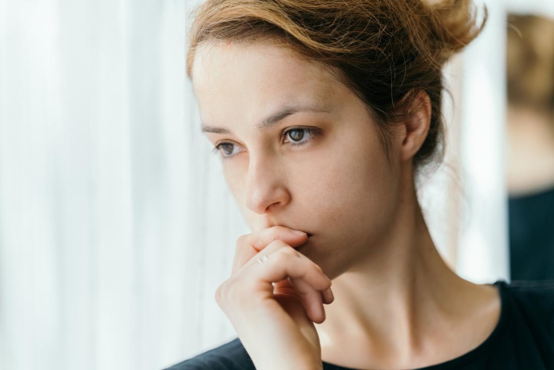 Woman experiencing brown discharge looking thoughtful.
