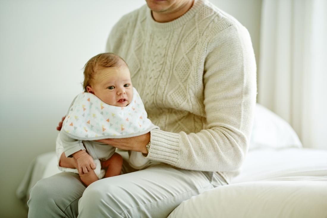 newborn baby sitting on parents lap