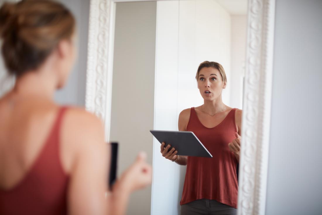 a woman practising talking in front of a mirror as that is How to stop stuttering