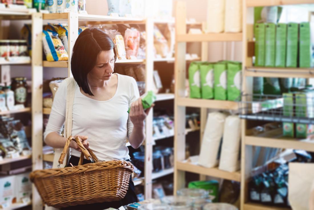 woman shopping for food reading ingredients label.