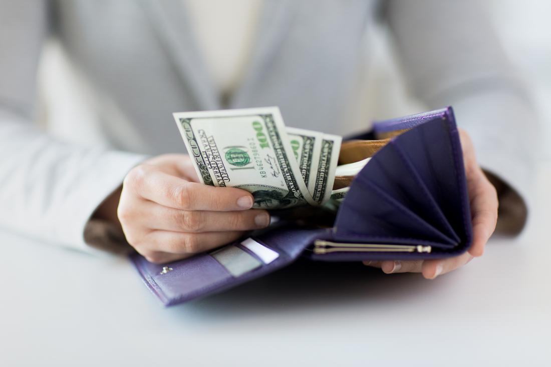 Woman taking hundred dollar bills out of her purse.