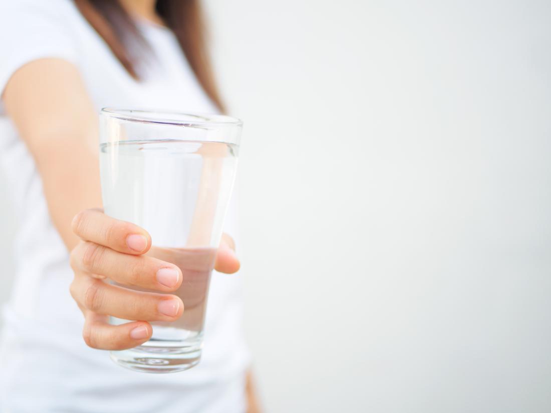 woman holding out a glass of water