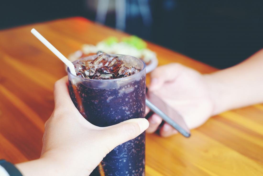 hand holding glass of cola
