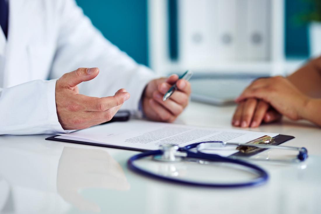 Doctor with clipboard on desk explaining results to patient.
