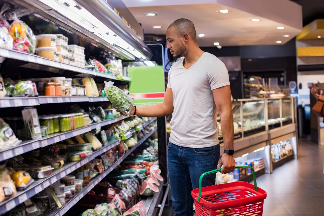 Man shopping for vegetables and salad in supermarket.
