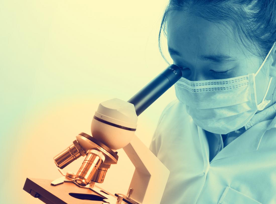 scientist looking through microscope