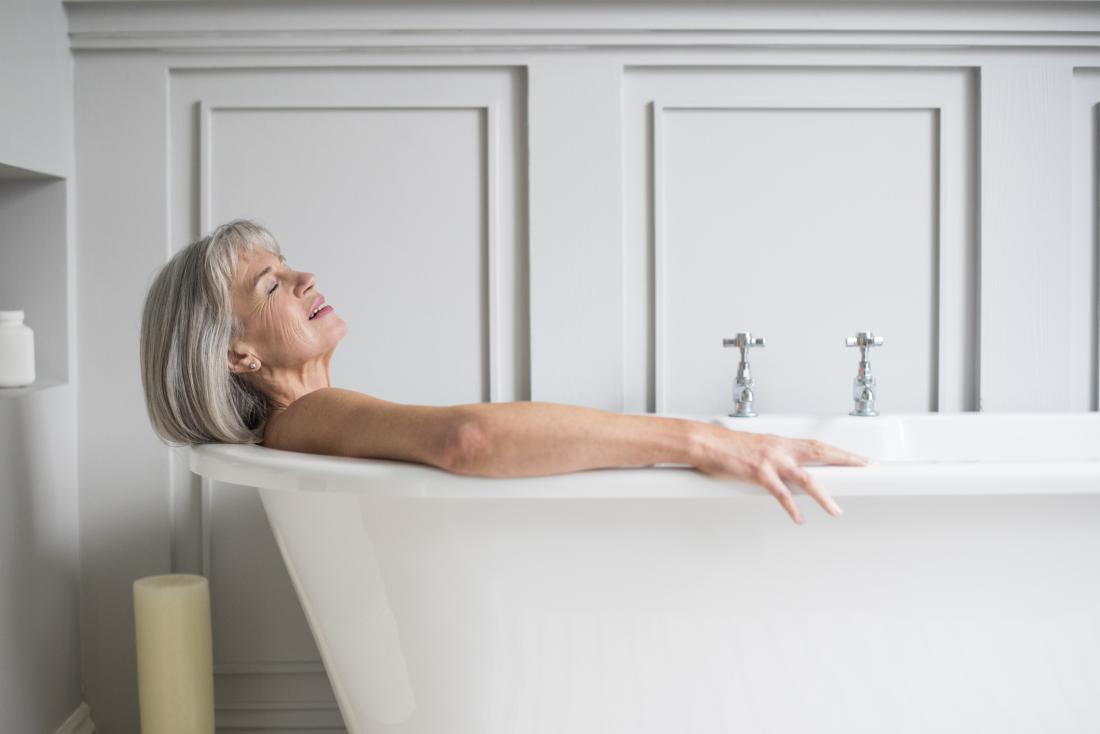 A Woman in a Bath with Towel. Girl Shows Hands in Form Heart