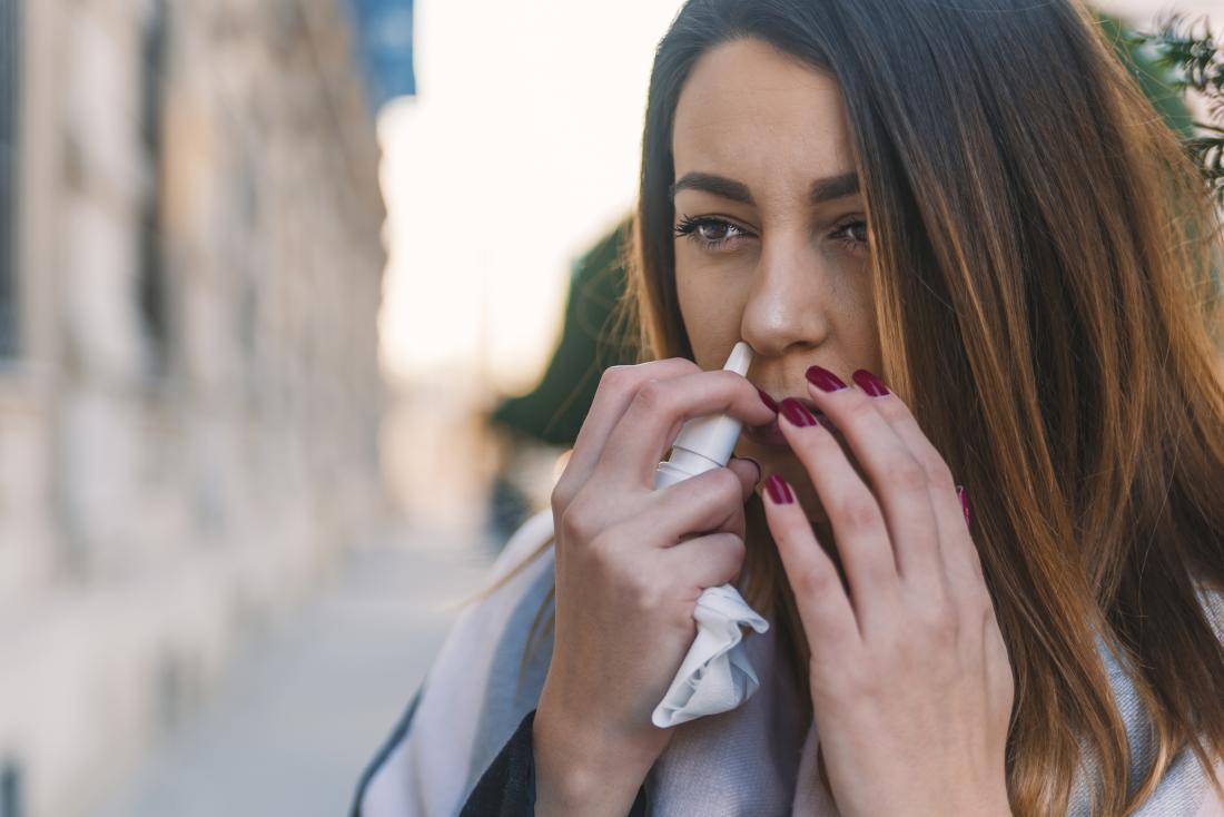 Woman outdoors using nasal spray