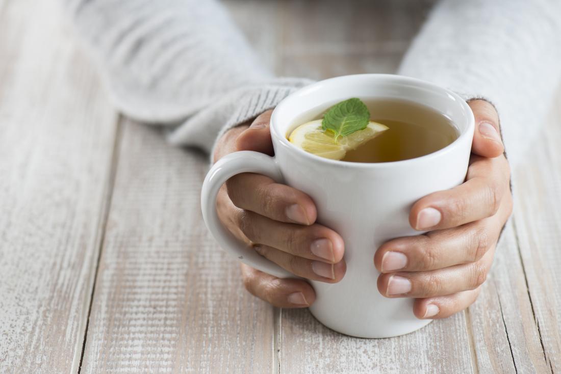 Woman holding mug or cup of herbal tea.