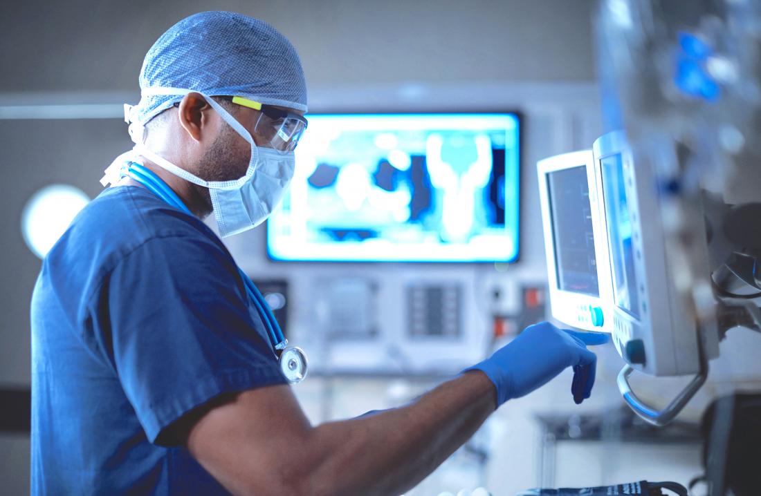 Surgeon preparing for bone graft in operating theatre touching monitor.