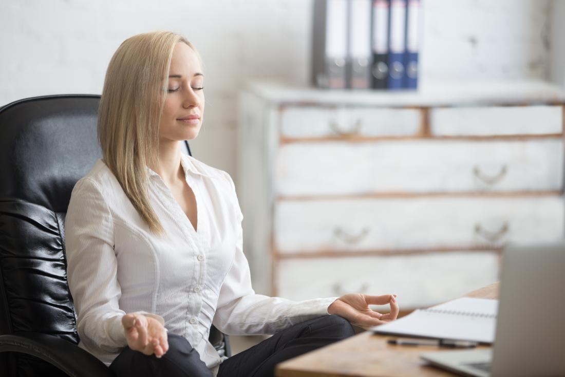 woman deep breathing and meditating at work