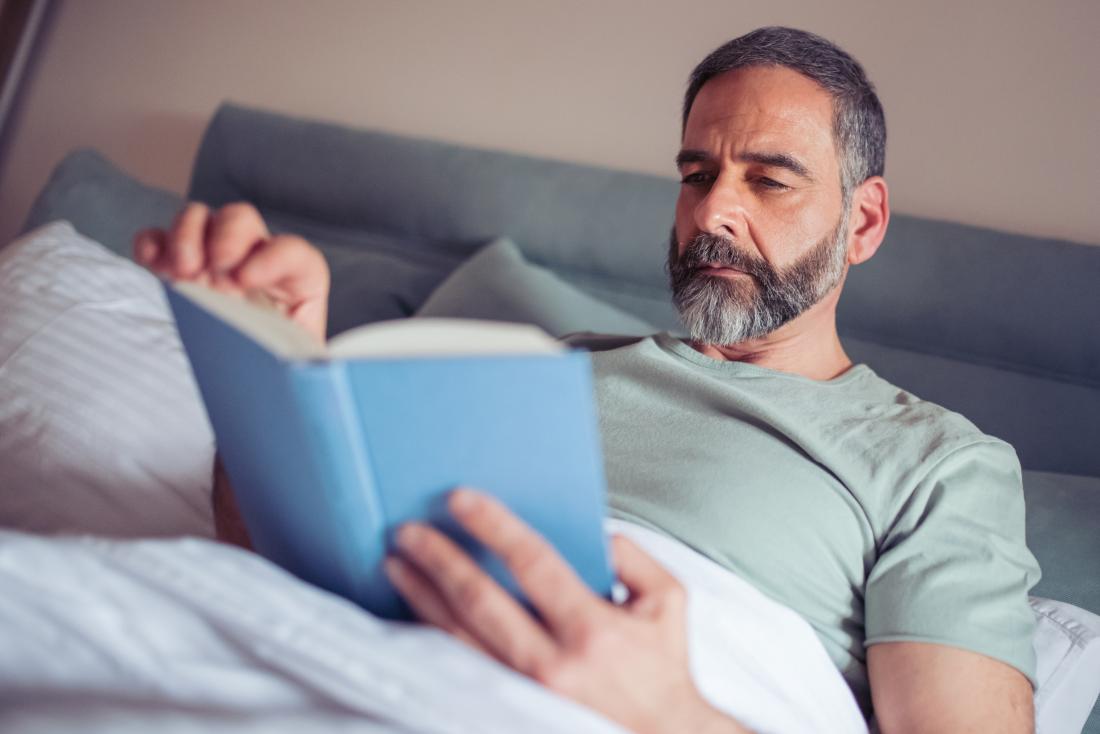 Male reading a book in bed