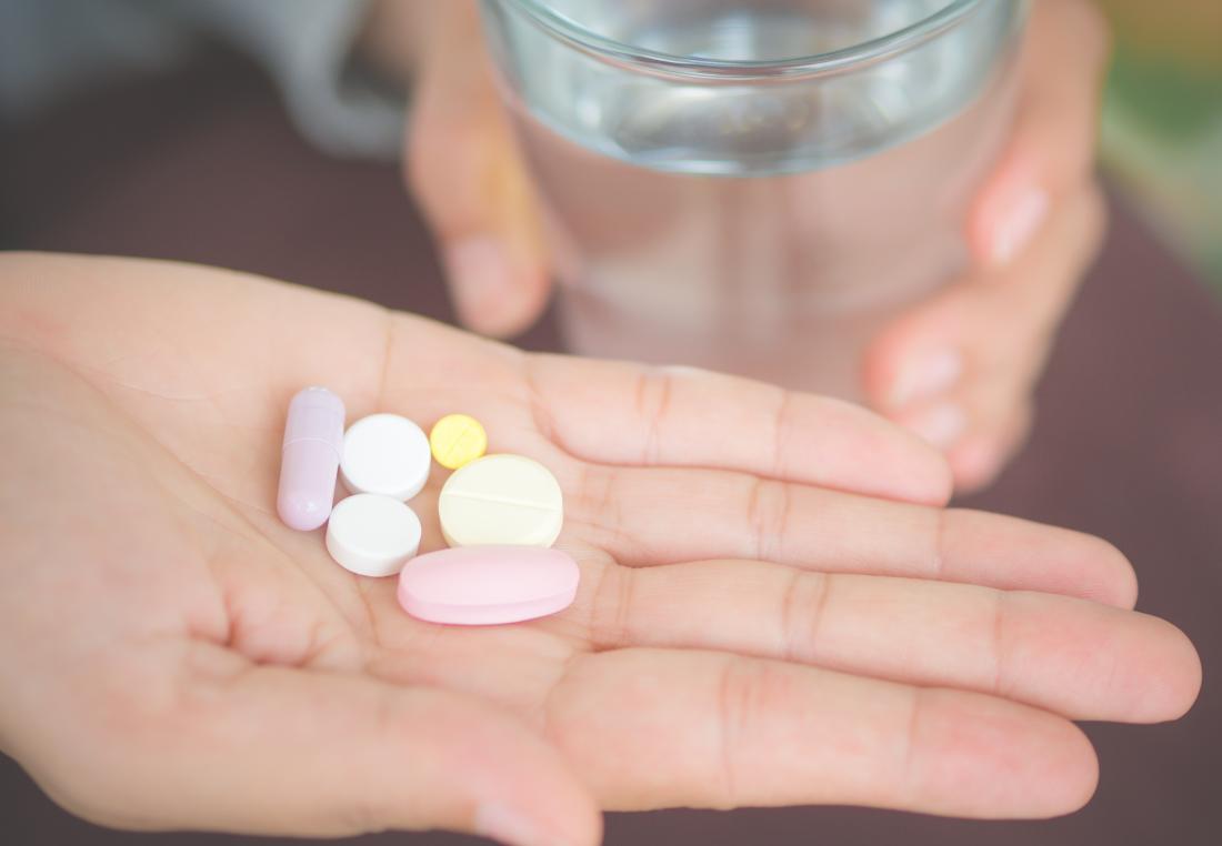 Different pills, vitamins, and supplements or medication in palm of hand