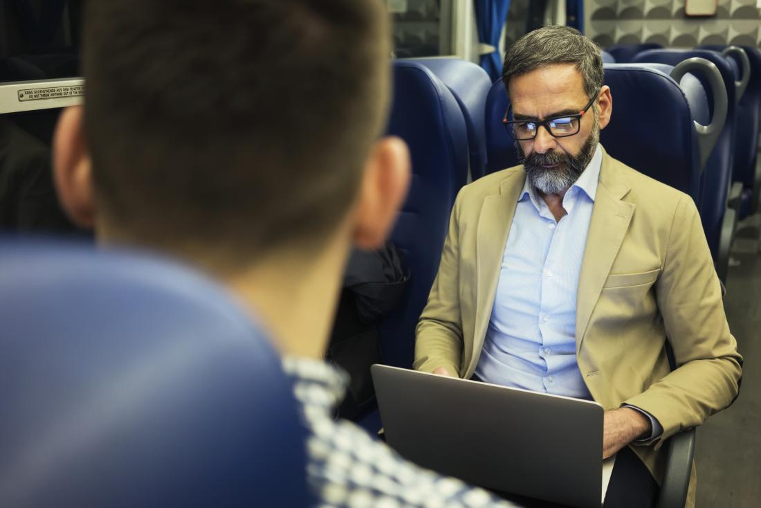 man sitting on train with laptop