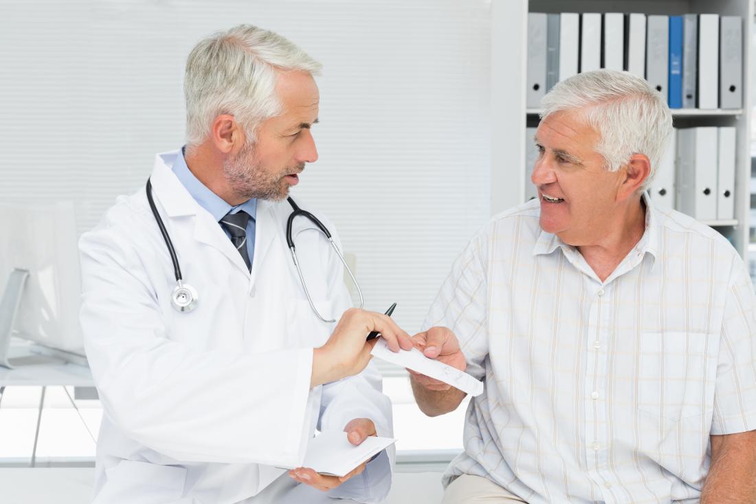 doctor handing male patient a prescription
