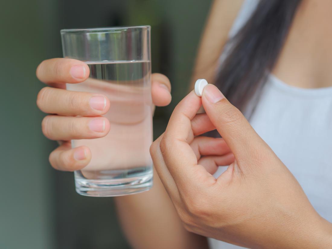 person taking a pill with water