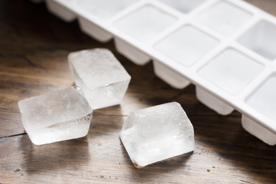 Ice cubes on wooden table next to tray