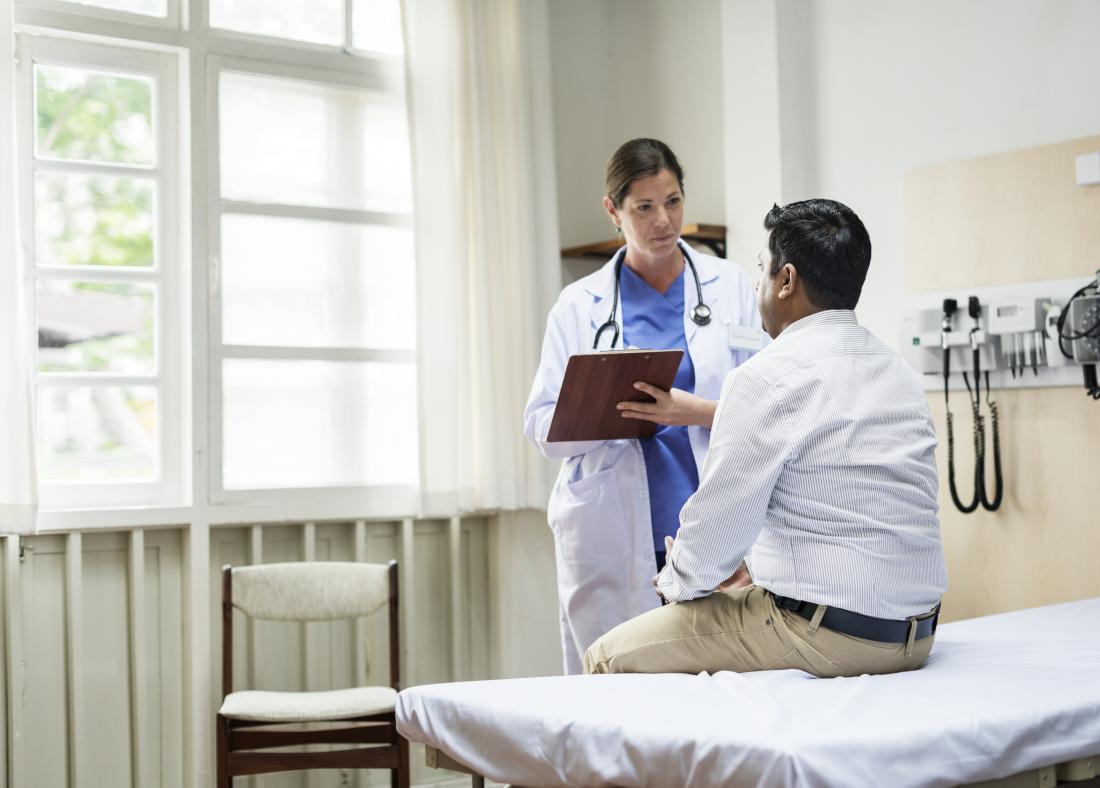 male patient sitting on examination table talking with physician