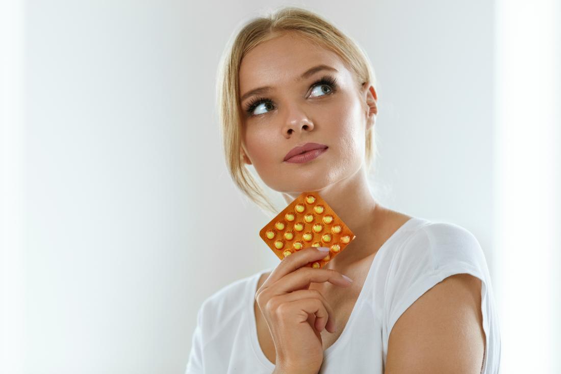 young woman holding pack of pills