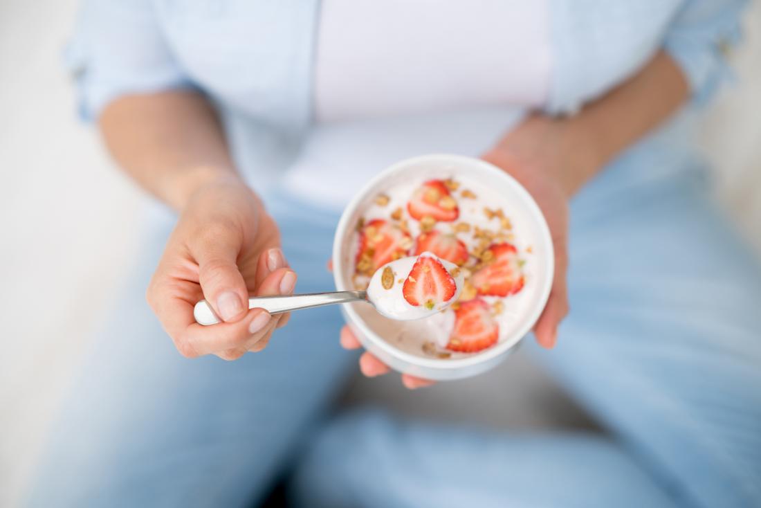 Person eating cereal with yoghurt and strawberry