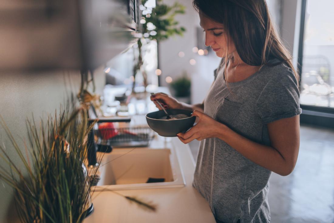 Femme prenant son petit déjeuner dans la cuisine.