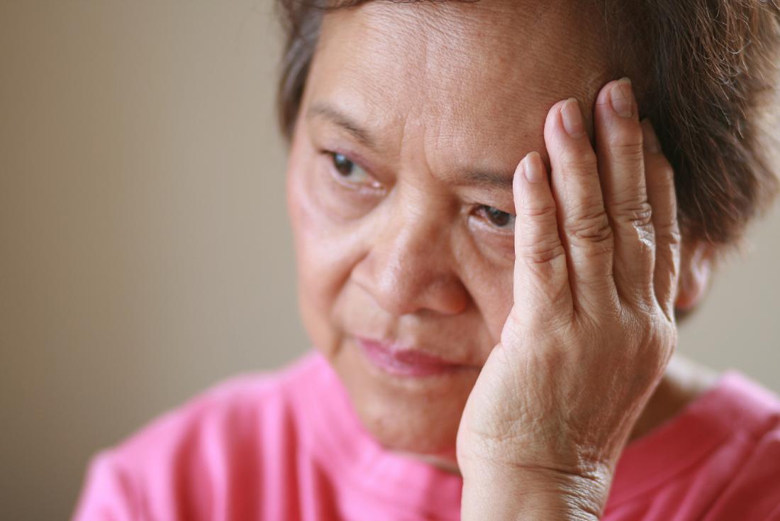 Senior woman holding head and looking worried, concerned or sad