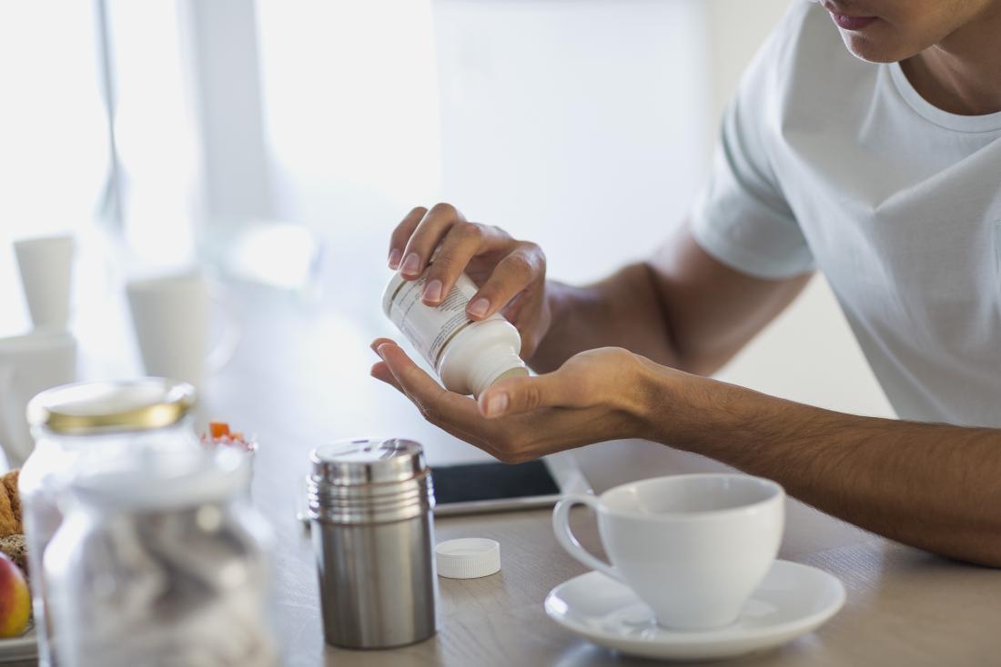 Man taking probiotic supplement at breakfast
