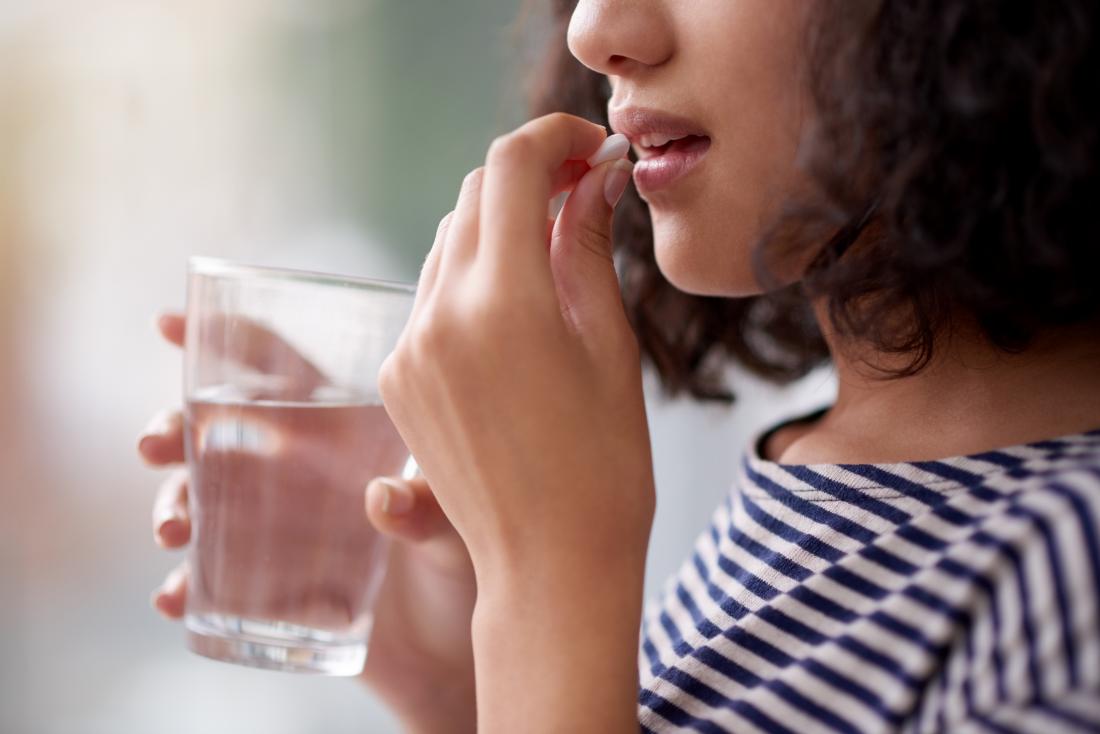 Woman taking a pill which is an anti-diarrheal treatment for crohn's