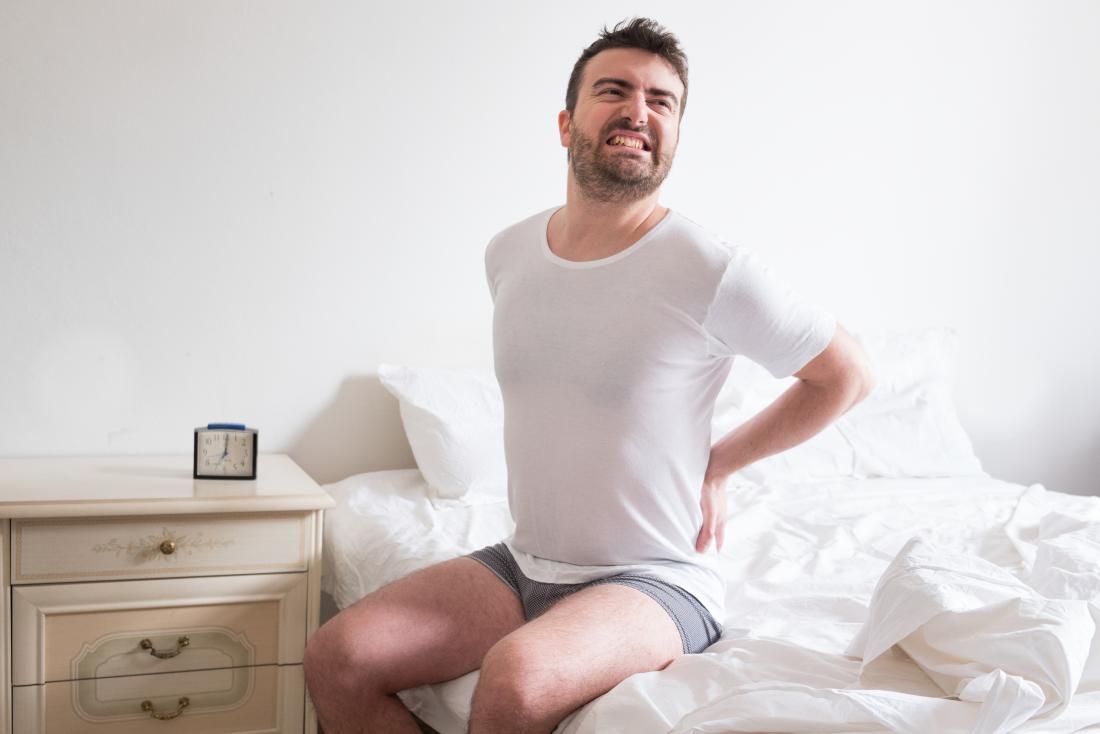 Man holding his back in pain due to psoriatic arthritis of the spine