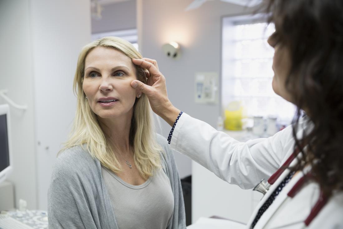 Doctor inspecting womans face