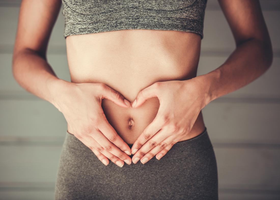 woman making a heart shape with her hands over her belly