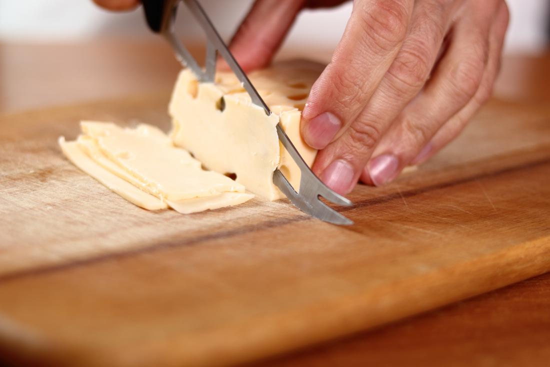 slicing swiss cheese on board