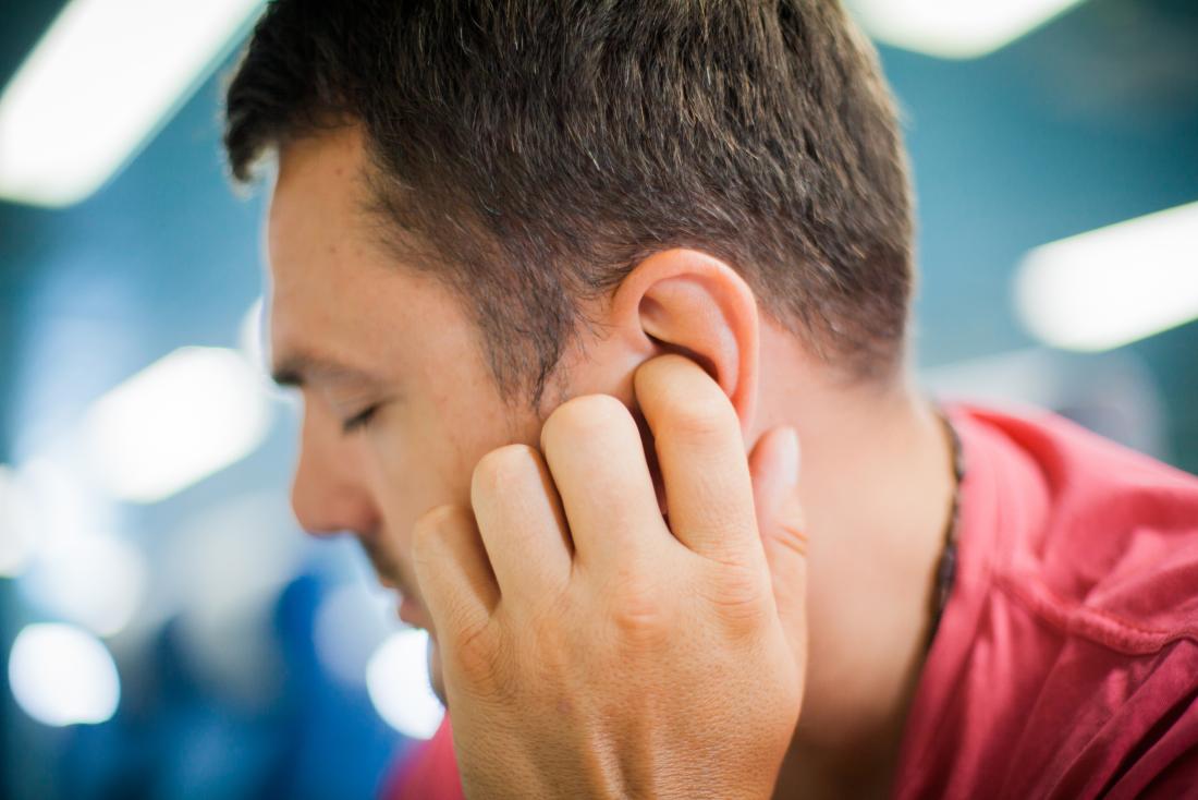 Man holding his ear due to ringing in the ear
