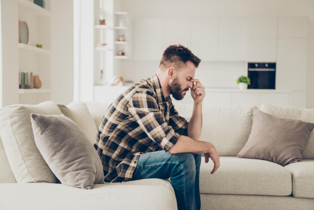 Man with a headache sat on his sofa