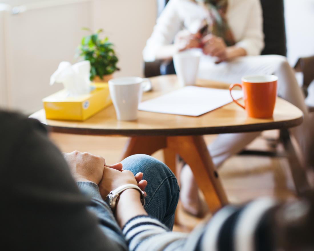 Couple in therapy holding hands opposite counselor