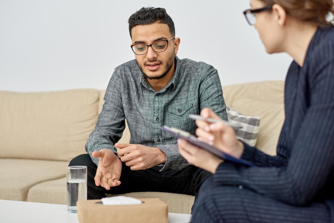 Young man in therapy session speaking to counselor during psychotherapy