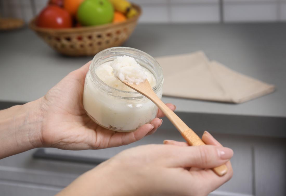 solid coconut oil being spooned out of jar