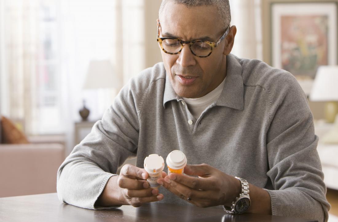 Man looking at pill bottles in home.