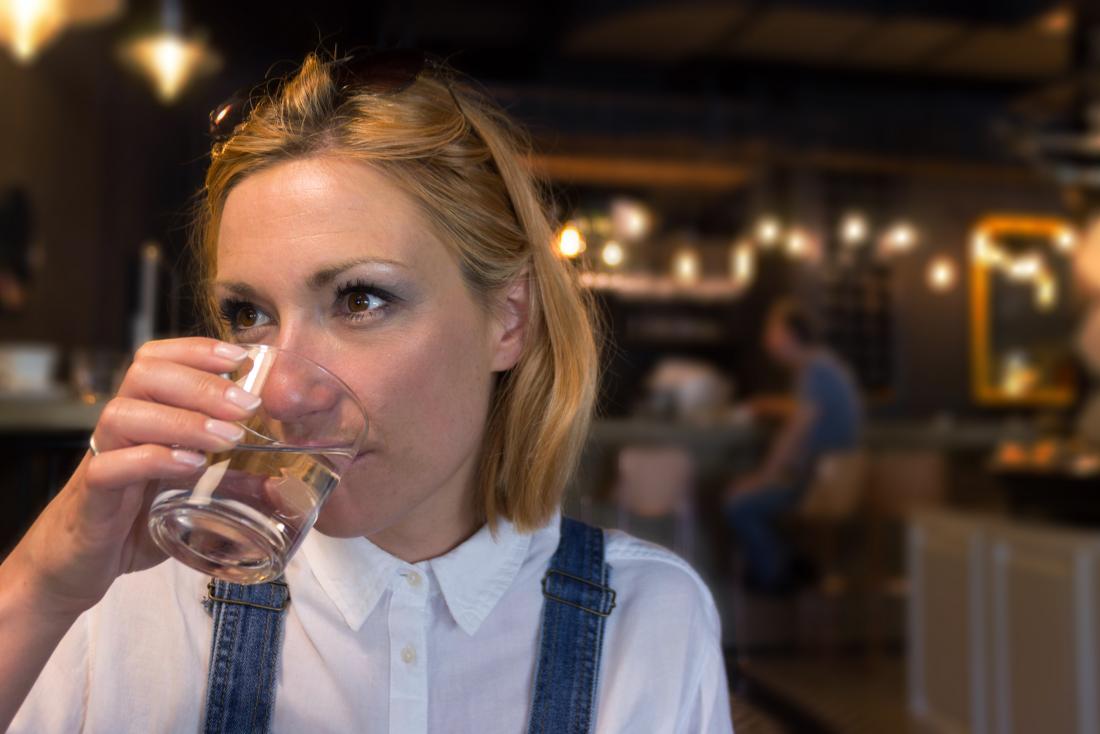 Woman drinking water in restaurant or bar