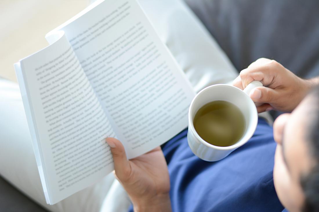 Person reading and drinking herbal tea top down view