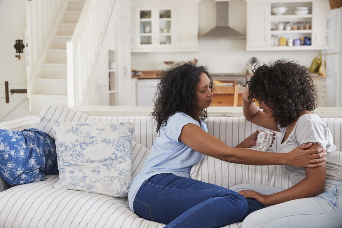 Family sitting on sofa in house comforting each other