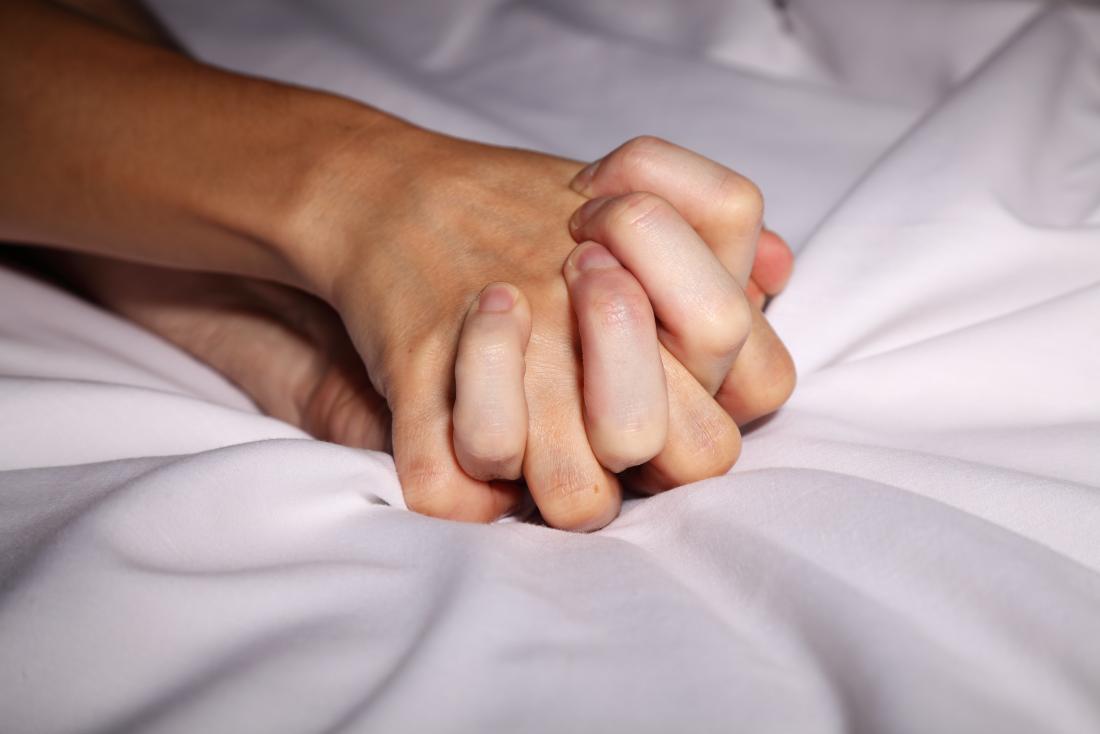 couple holding hands in bed during sex