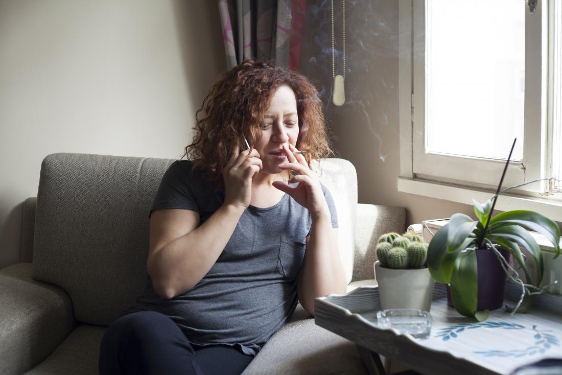 Middle aged woman smoking indoors and talking on the phone