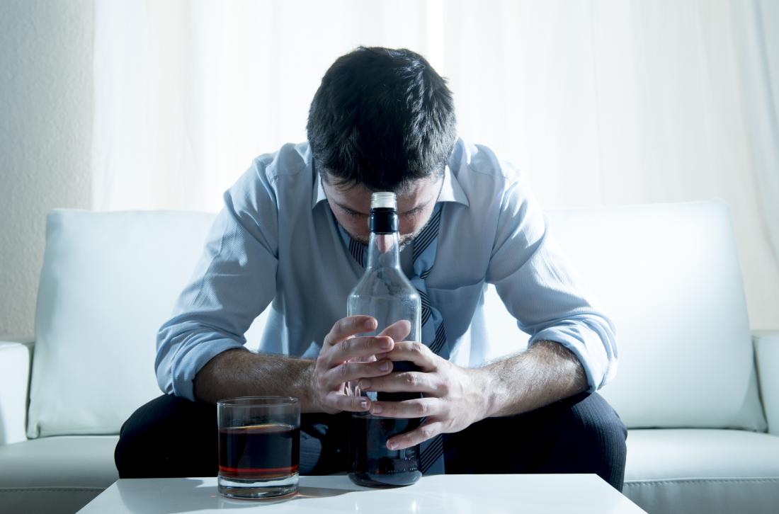 man clutching a bottle with his head down