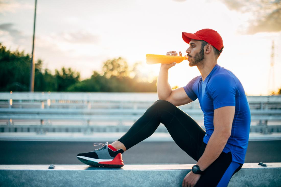 Athlete drinking sports energy drink after exercising.