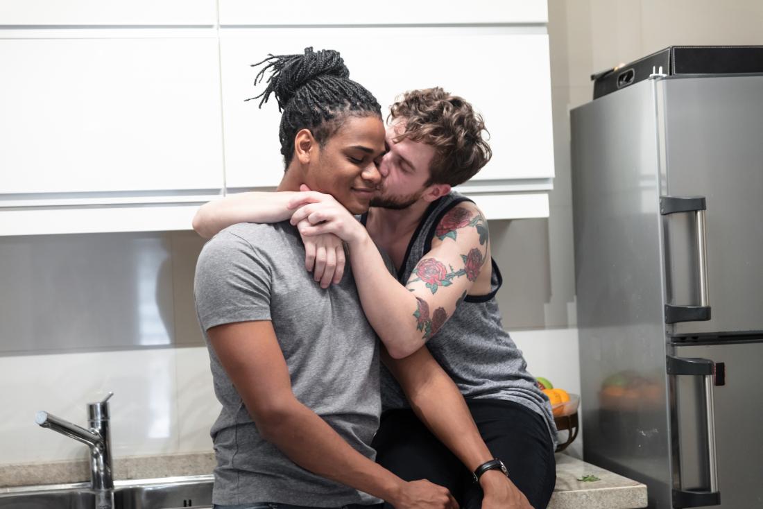 Gay or LGBT couple in kitchen kissing.